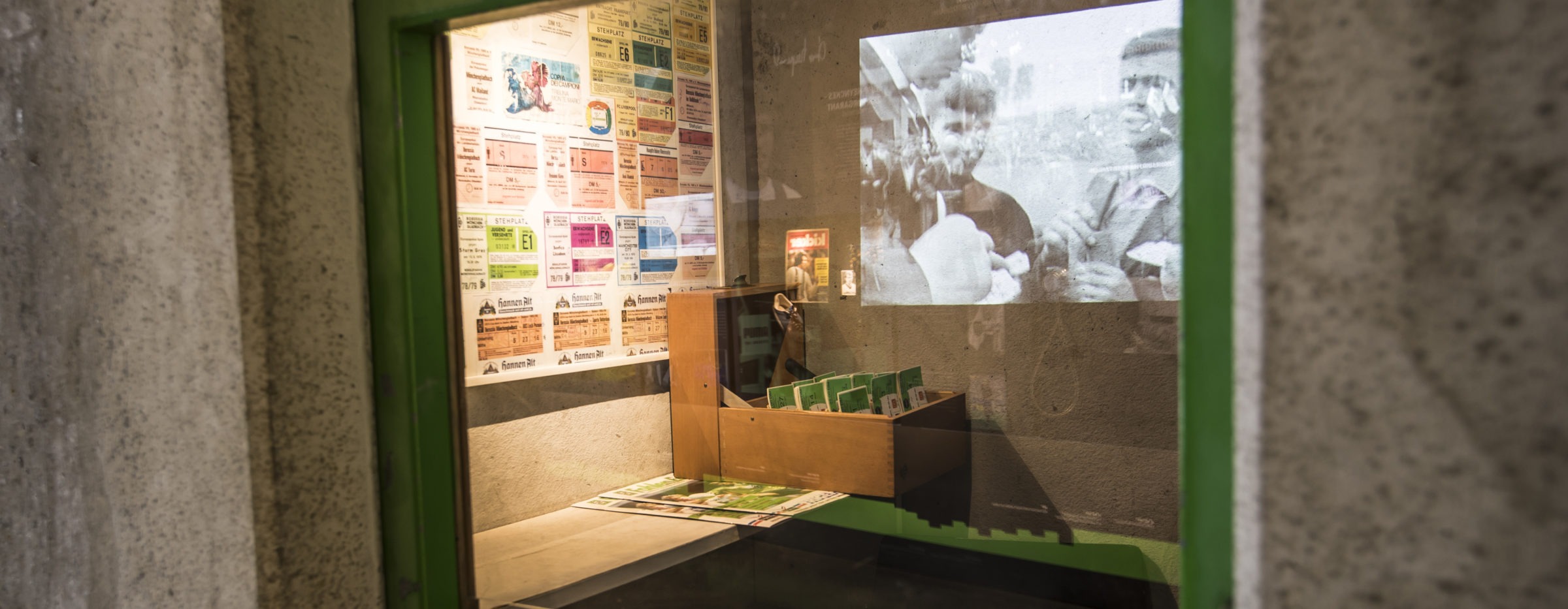 Vitrine mit Videoleinwand und alten Exponaten